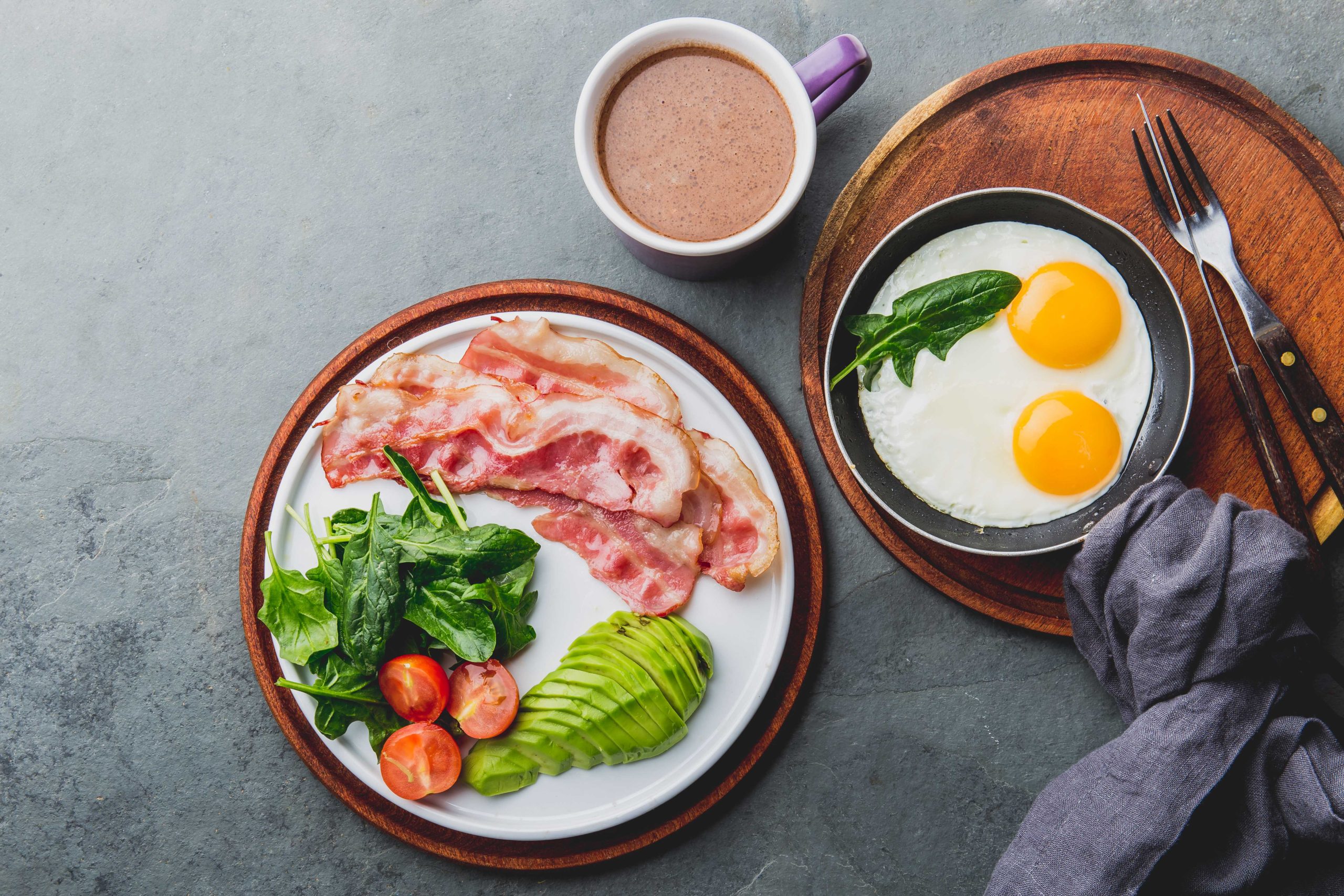 Кетогенный диетический завтрак. жареное яйцо, бекон и авокадо, шпинат и пуленепробиваемый кофе.