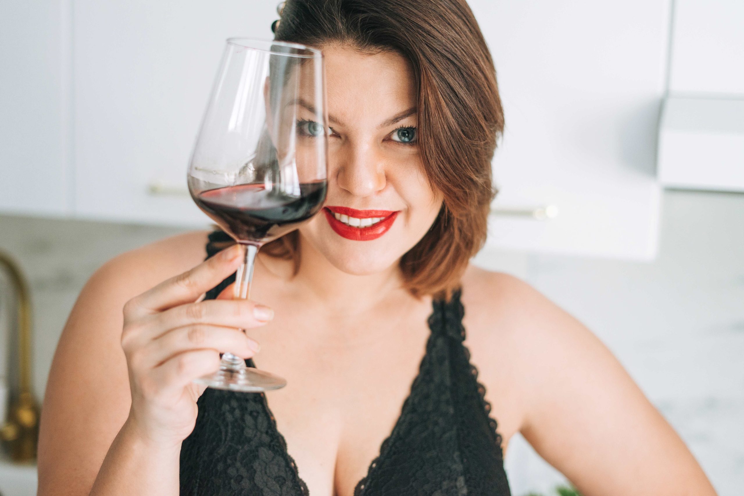 Молодая женщина плюс размер тела положительный с бокалом красного вина